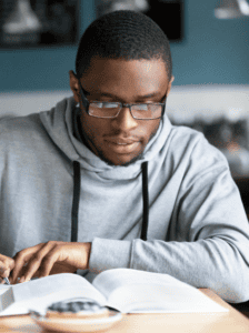 A man deeply immersed in the open book lying on the surface in front of him